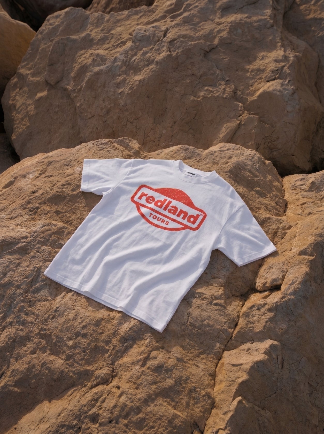 T-shirt bianca con logo rosso Redland Tours effetto timbro.