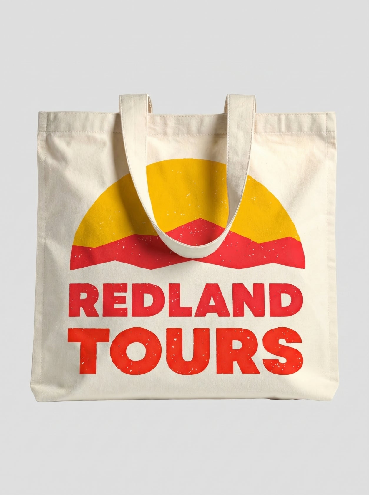 Tote bag naturale Redland Tours con grafica sole giallo e dune rosse.