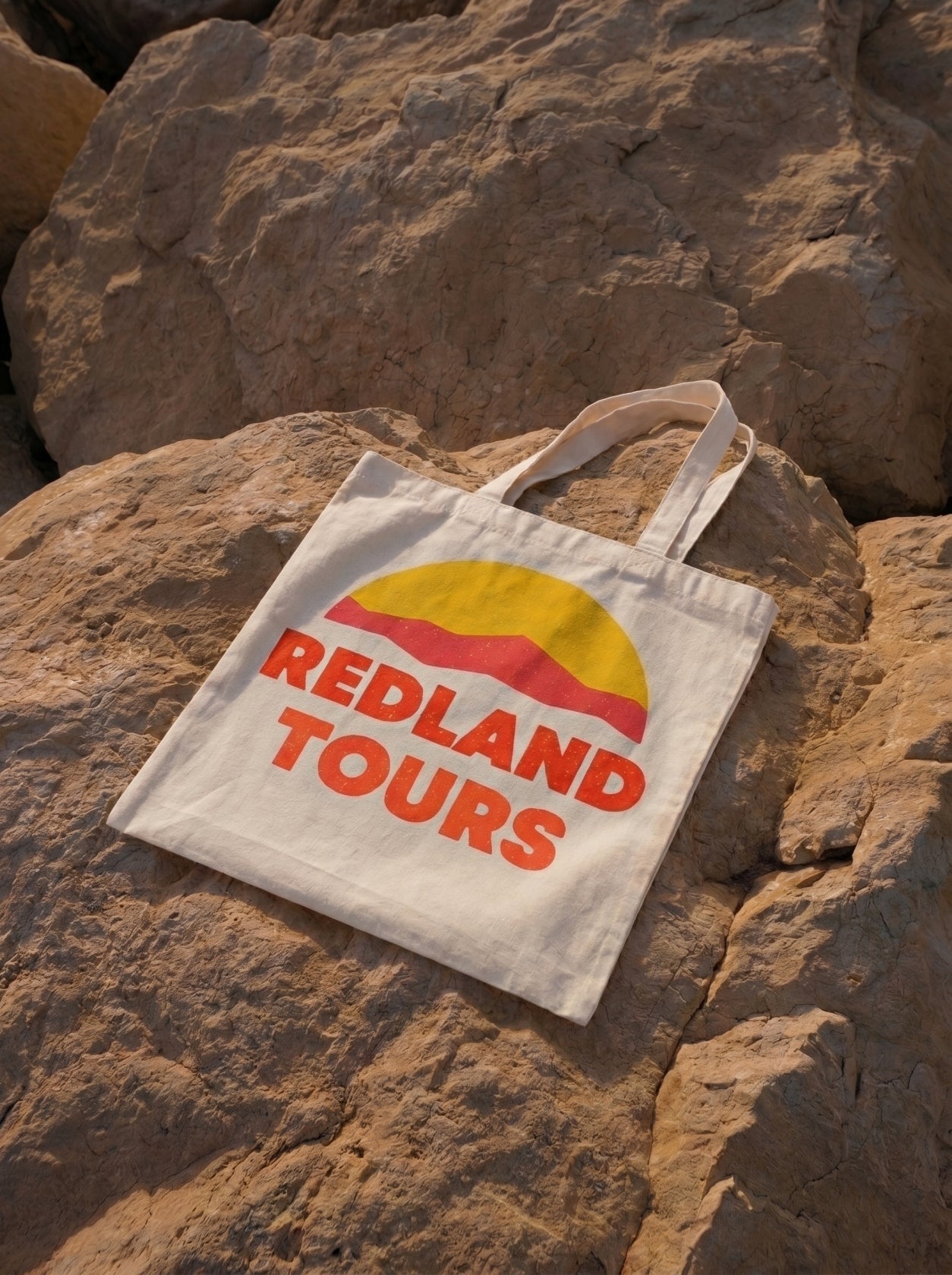 Tote bag naturale Redland Tours con grafica sole giallo e dune rosse.