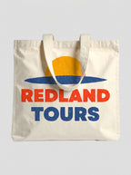 Tote bag naturale Redland Tours con grafica sole giallo, orizzonte blu e lettering rosso.