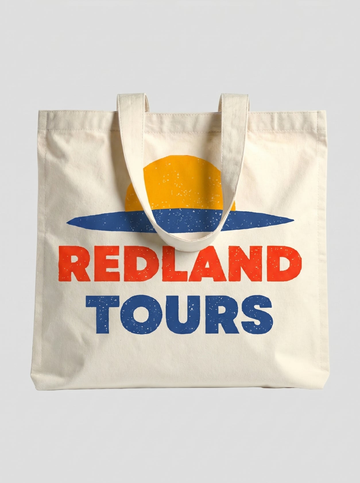 Tote bag naturale Redland Tours con grafica sole giallo, orizzonte blu e lettering rosso.