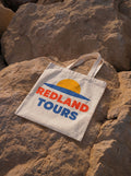 Tote bag naturale Redland Tours con grafica sole giallo, orizzonte blu e lettering rosso.