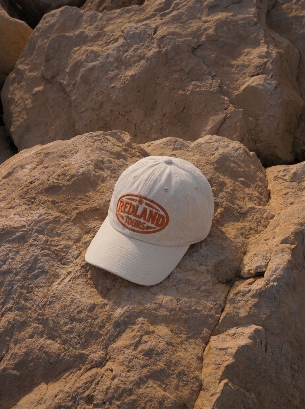 Cappellino beige Redland Tours con logo ovale ricamato arancio.