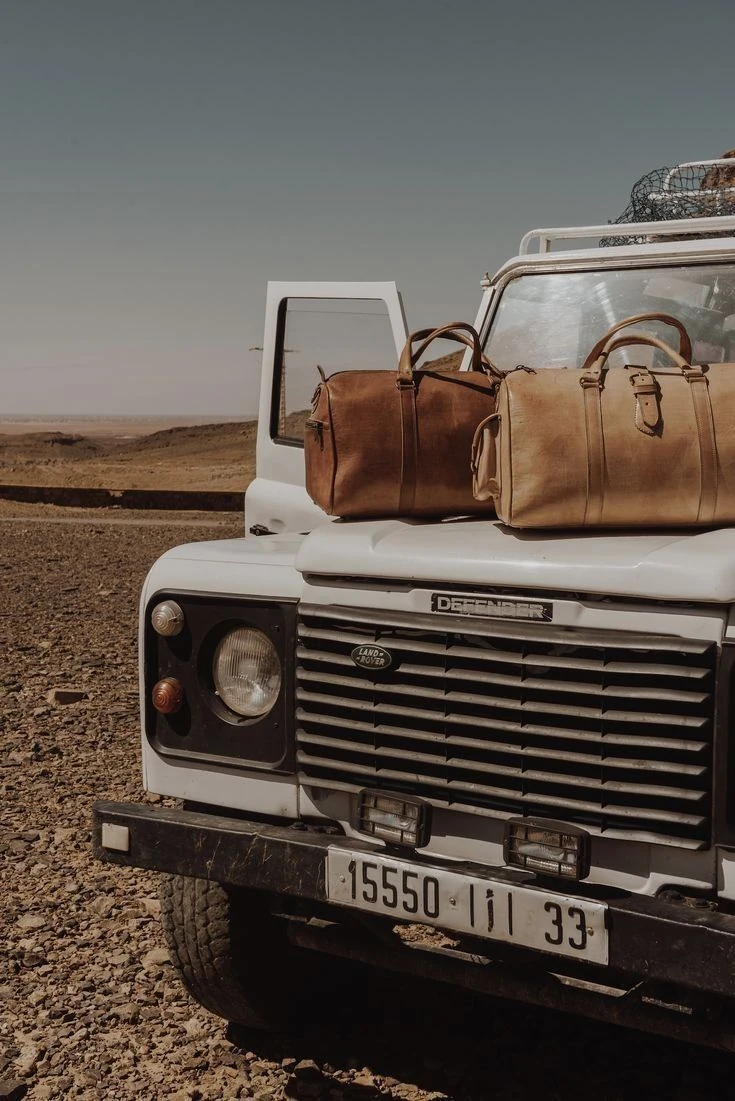 Borse da viaggio sul cofano di un fuoristrada, in un paesaggio arido
