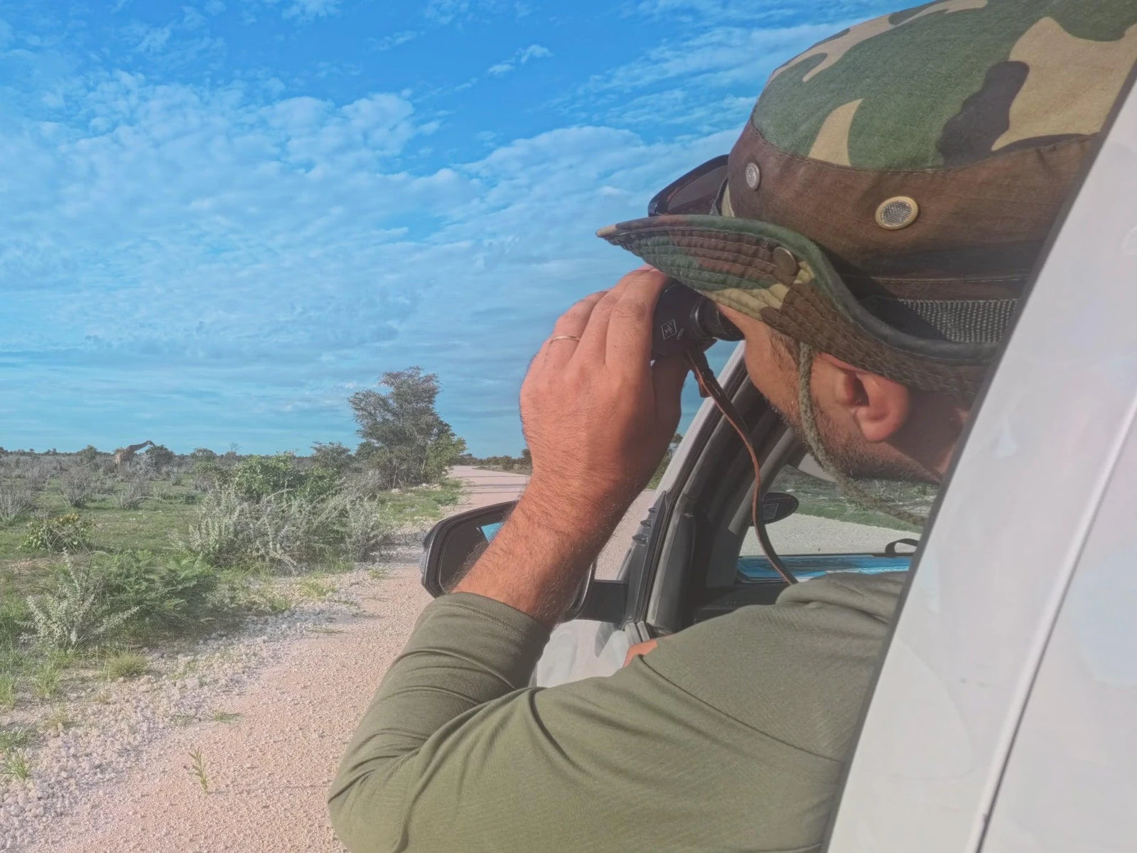 A traveler with binoculars from an off-road vehicle in Namibia