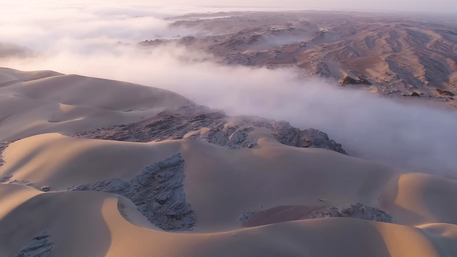 Eine Luftaufnahme zwischen Dünen und Nebel der namibischen Küste