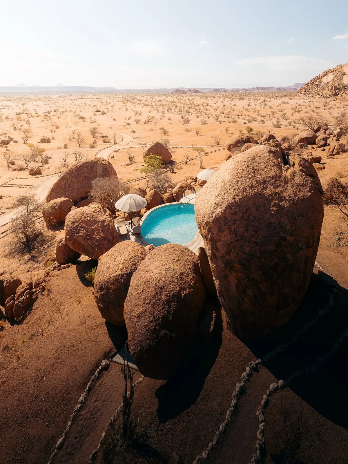 Schwimmbad zwischen großen Felsen mit Blick auf die Wüstenlandschaft