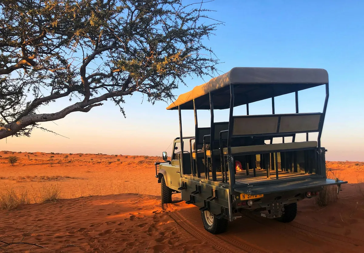 Ein offenes Safarifahrzeug mit mehreren Sitzreihen im Abendlicht der namibischen Kalahari