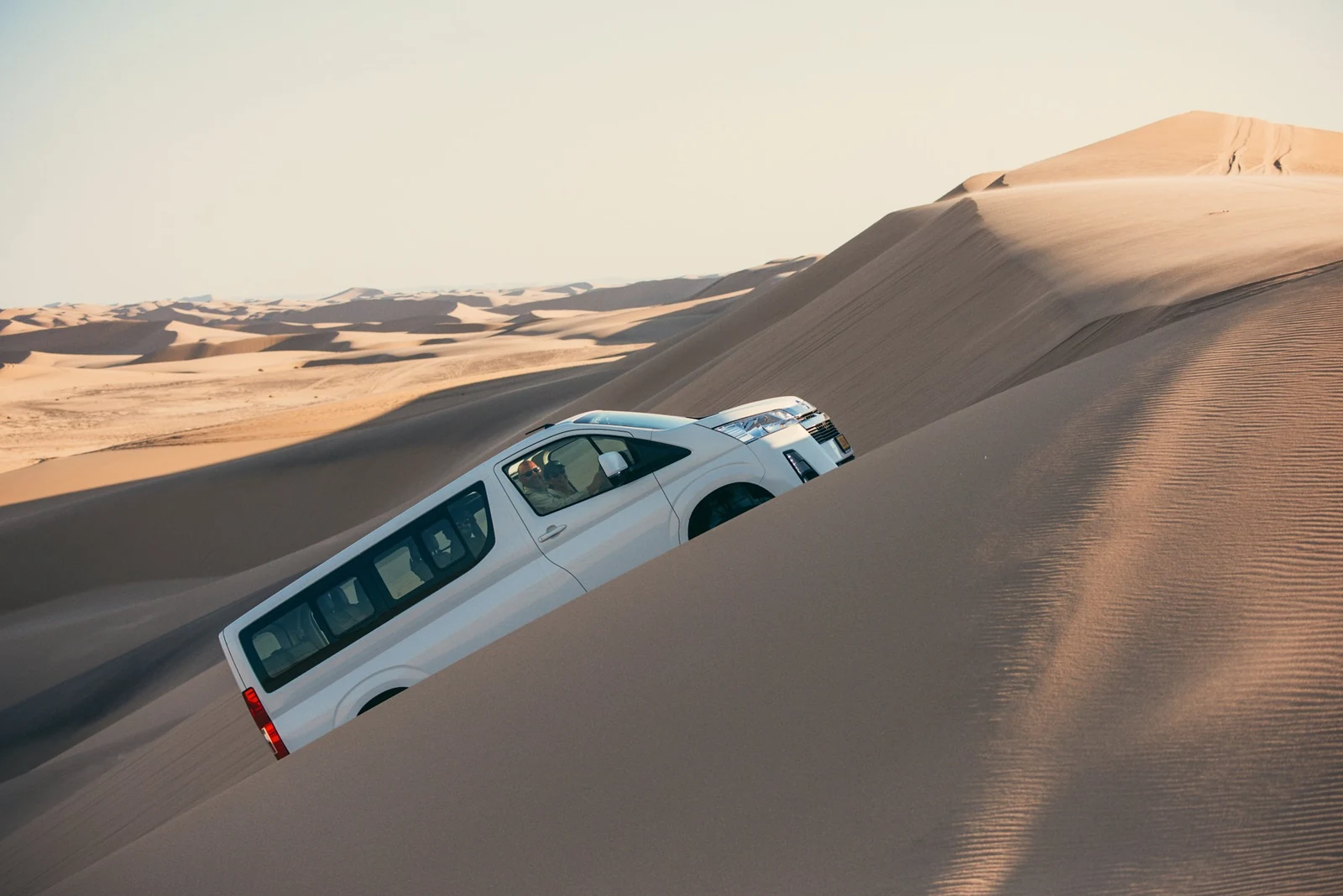 A Toyota Quantum 4x4 minivan climbs a Namib dune in the afternoon light
